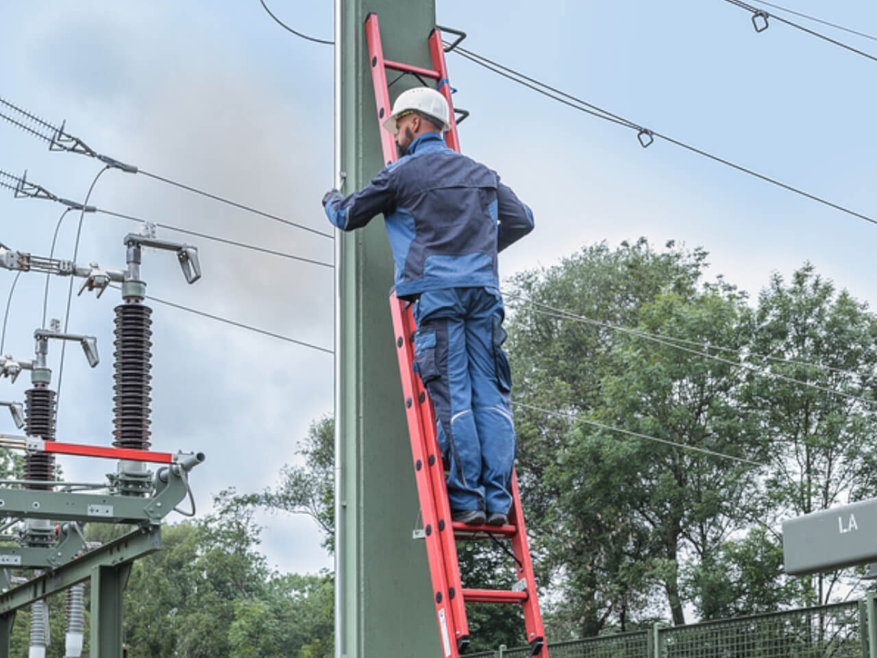 handwerker steht auf einer gfk schiebeleiter fuer umgebungen bis 28000 volt